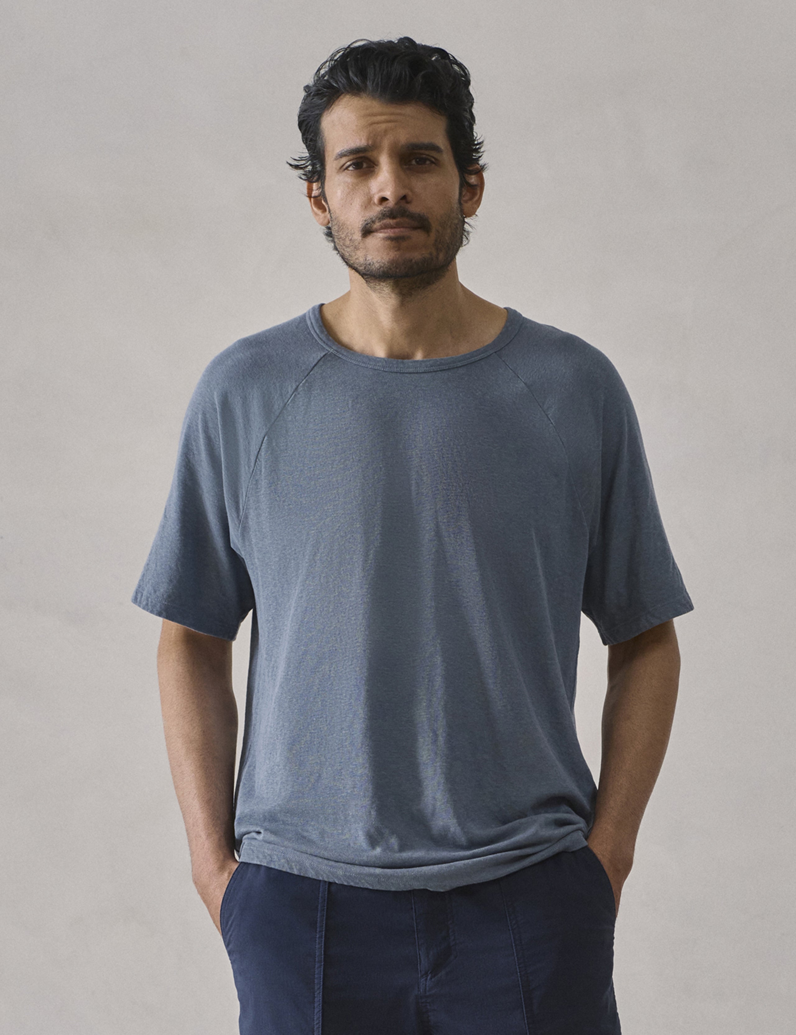 Front upper-body view of man wearing Buckhorn Cotton Raglan Tee 2.0 in Portal Blue from AETHER Apparel.