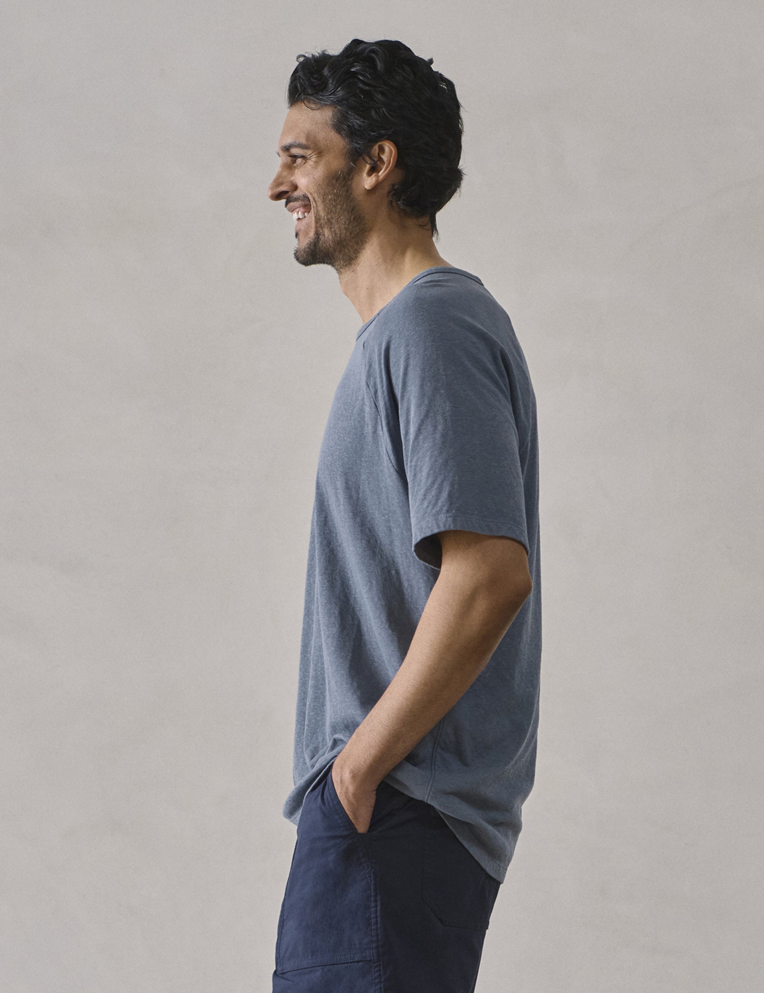 Side profile upper-body view of man wearing Buckhorn Cotton Raglan Tee 2.0 in Portal Blue from AETHER Apparel.