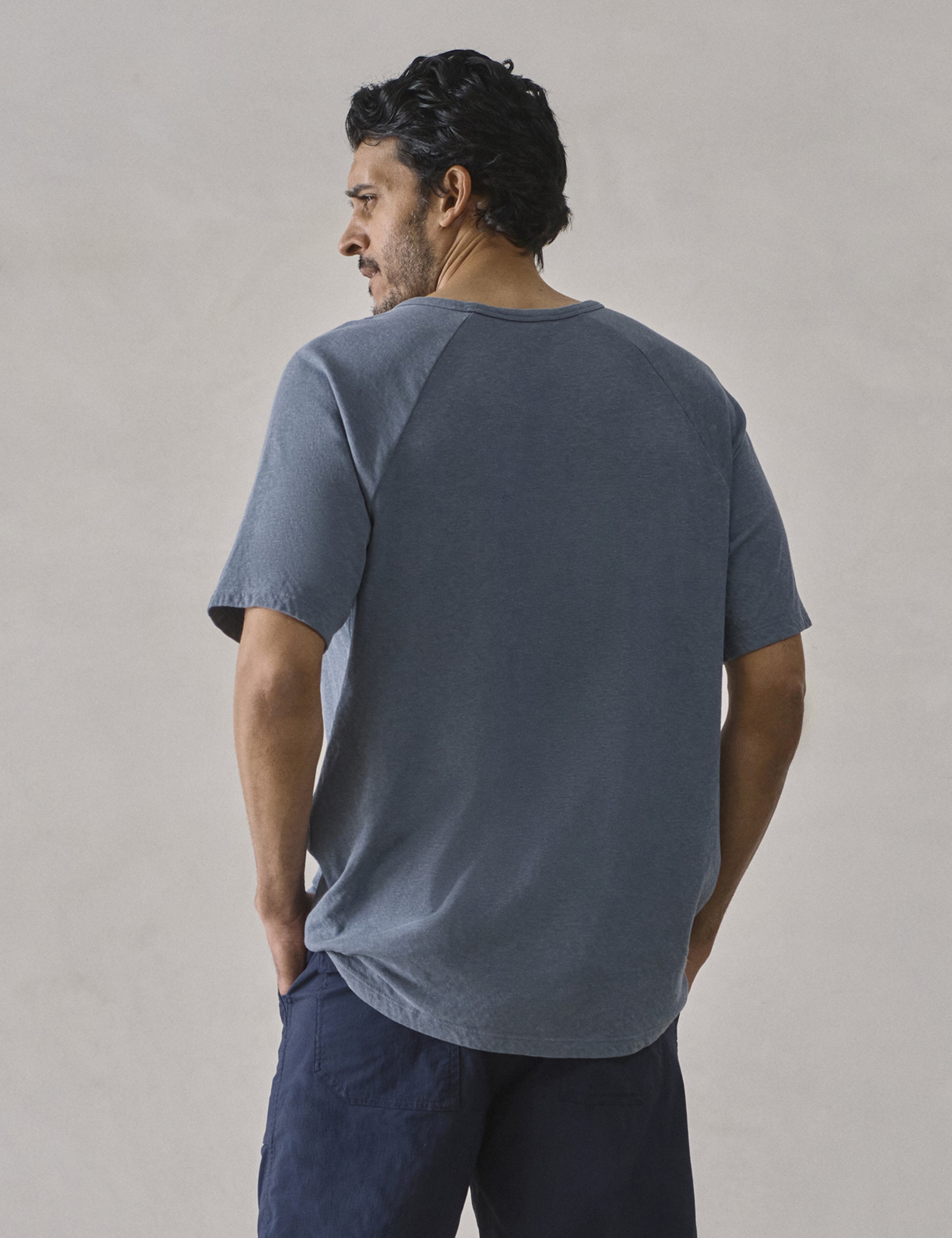 Rear upper-body view of man wearing Buckhorn Cotton Raglan Tee 2.0 in Portal Blue from AETHER Apparel.