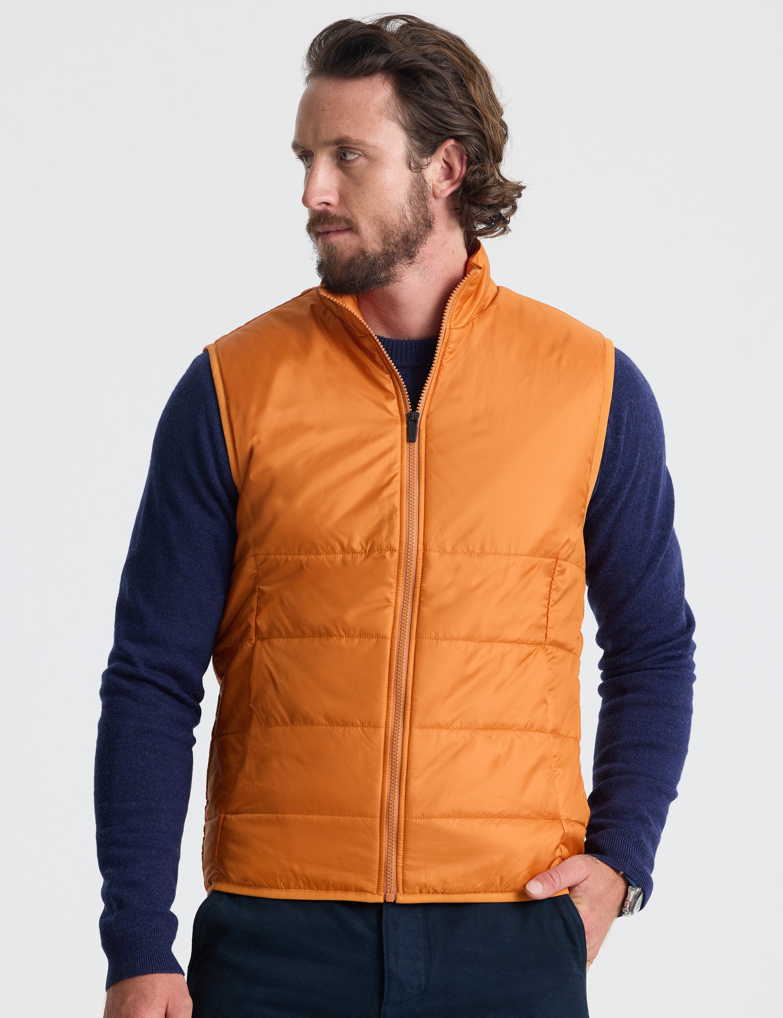 Front view of man wearing Eco Insulated Vest in Autumn Orange from AETHER Apparel.