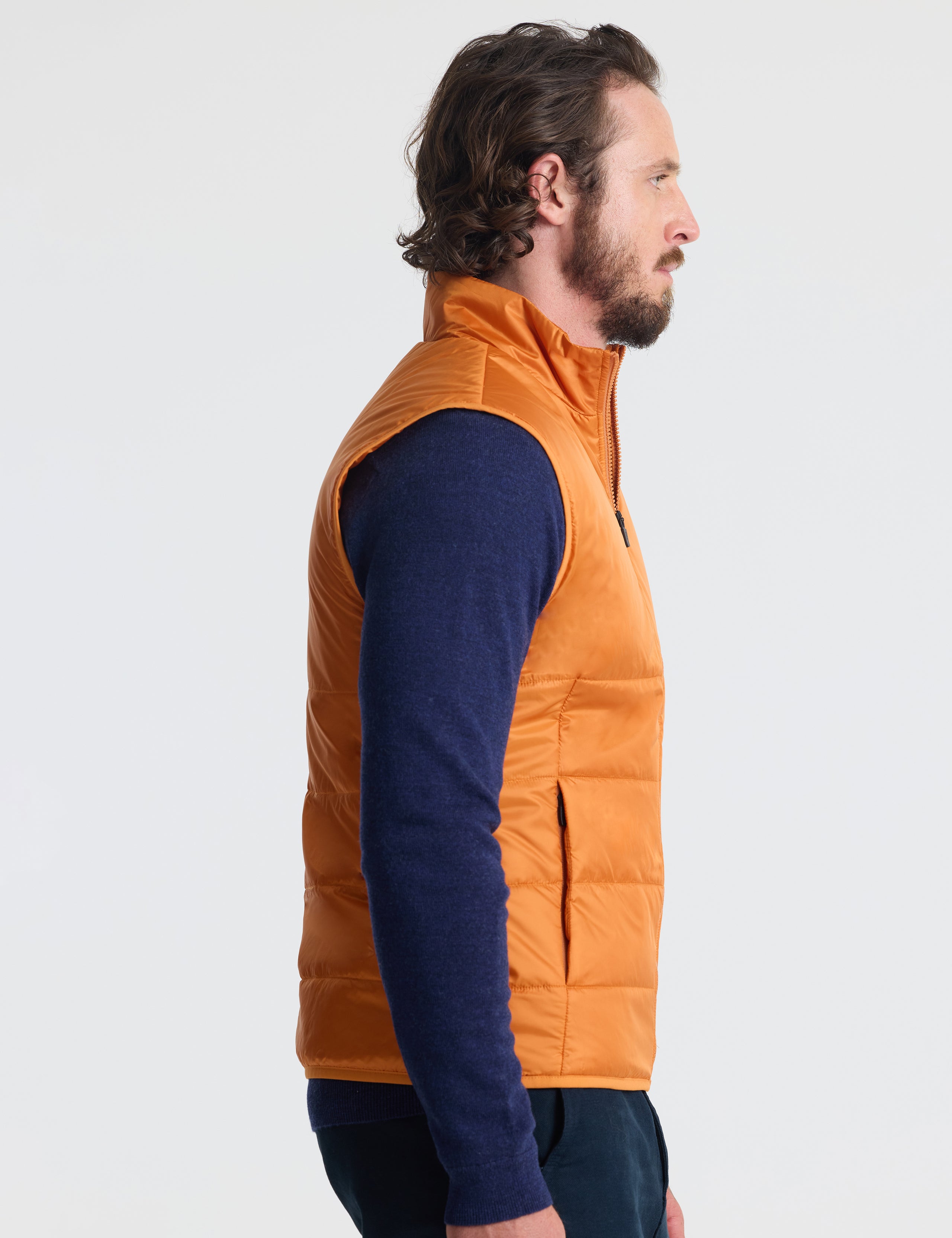 Right profile of man wearing Eco Insulated Vest in Autumn Orange from AETHER Apparel.