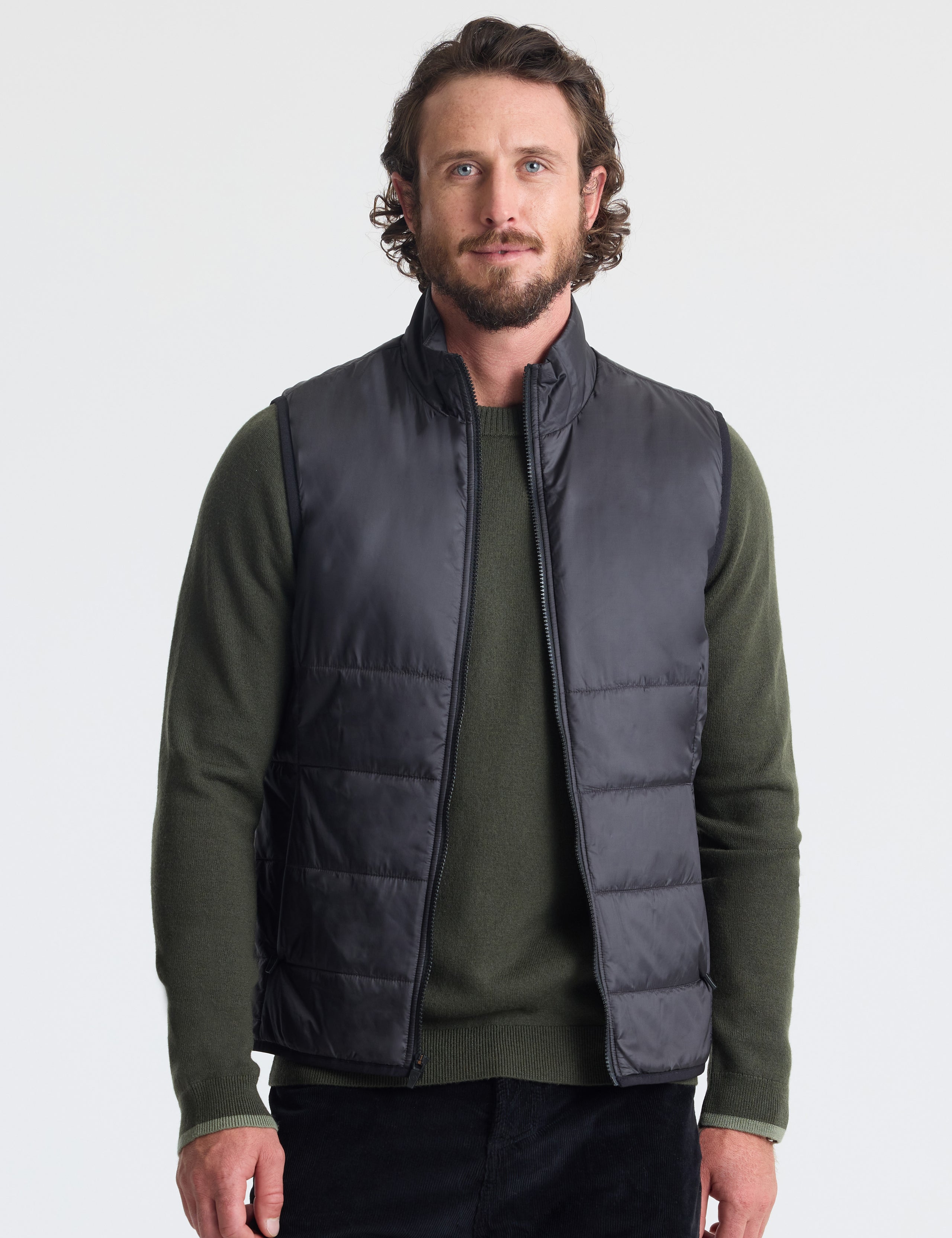 Upper body view man wearing unzipped Eco Insulated Vest in Onyx Black from AETHER Apparel.