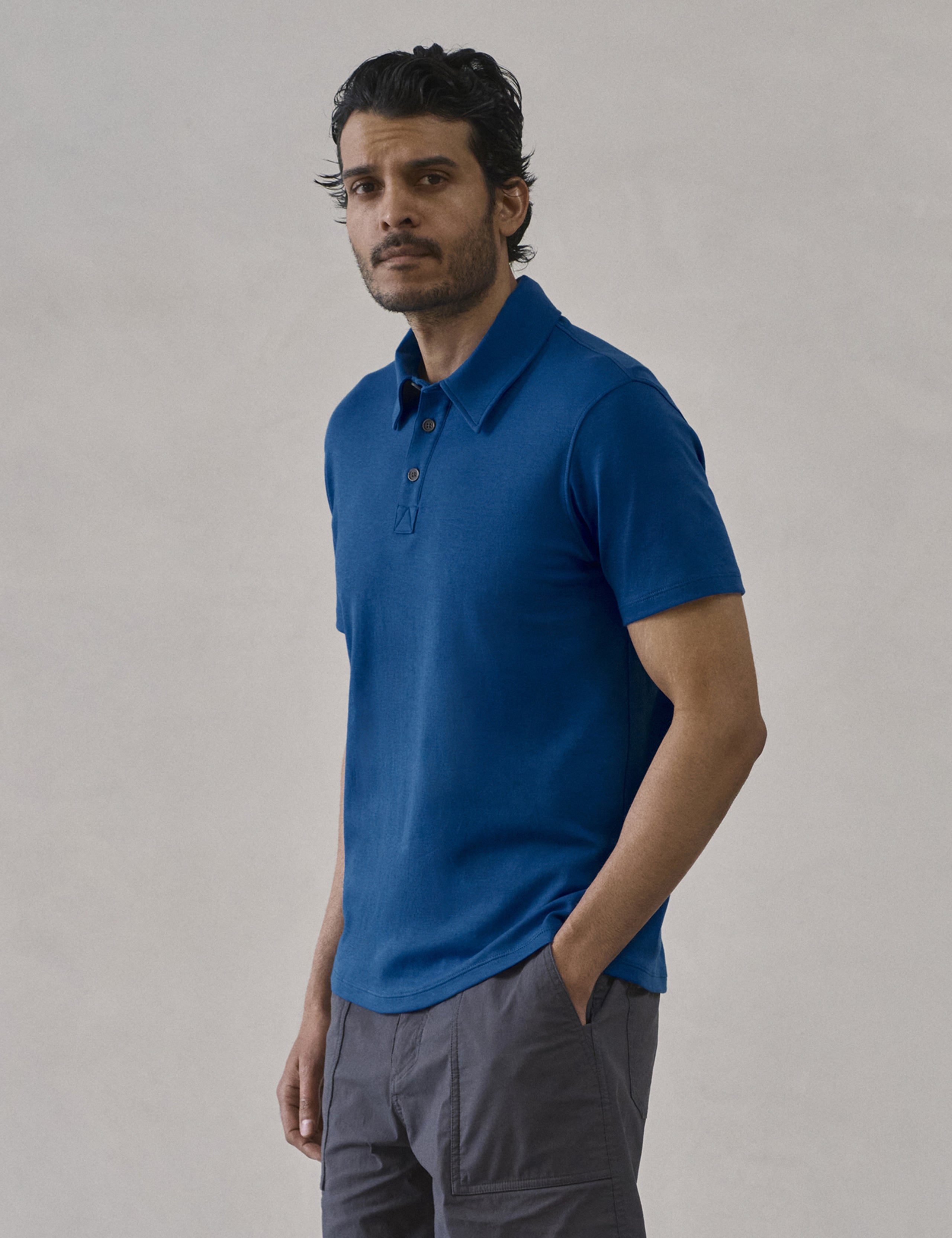 Front 3/4 body view of man wearing Emery Pima Polo in Summit Blue from AETHER Apparel.