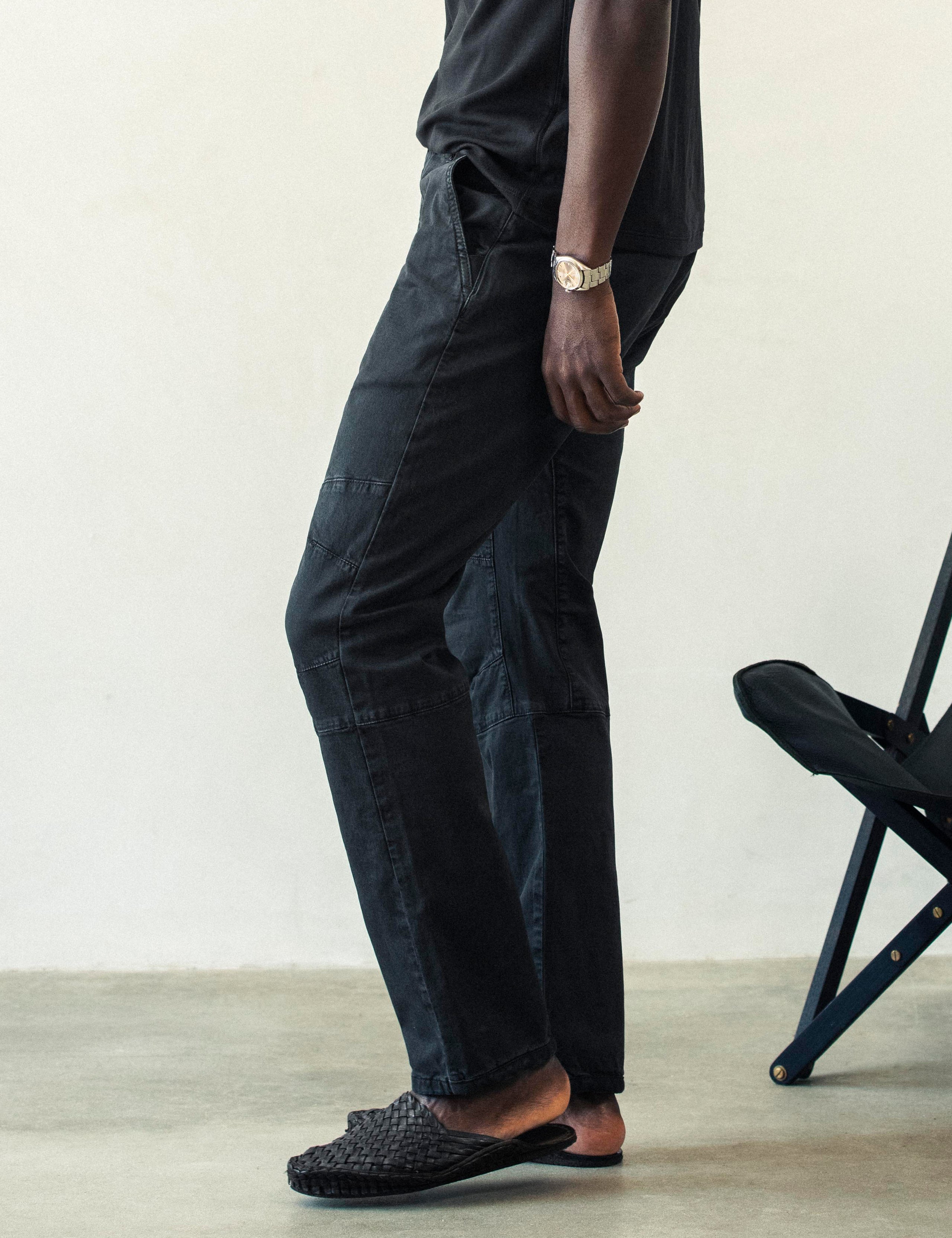 Side profile lower body view of man wearing Gabriel Articulated Chino Stretch pant in Tarmac Black from AETHER Apparel.