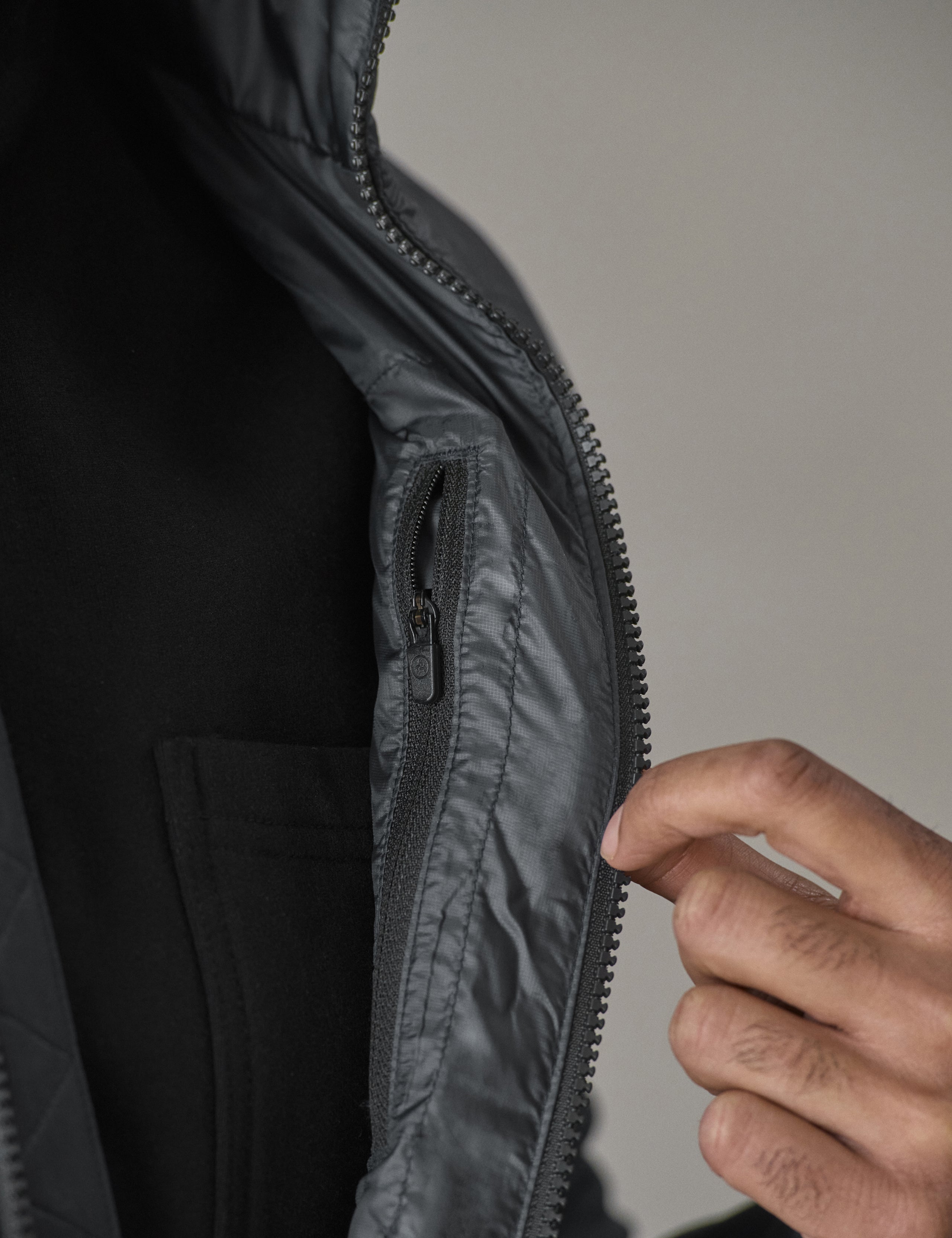 Closeup detailed view of the interior zippered pocket on the Hybrid Tech Full-Zip in Graphite from AETHER Apparel.