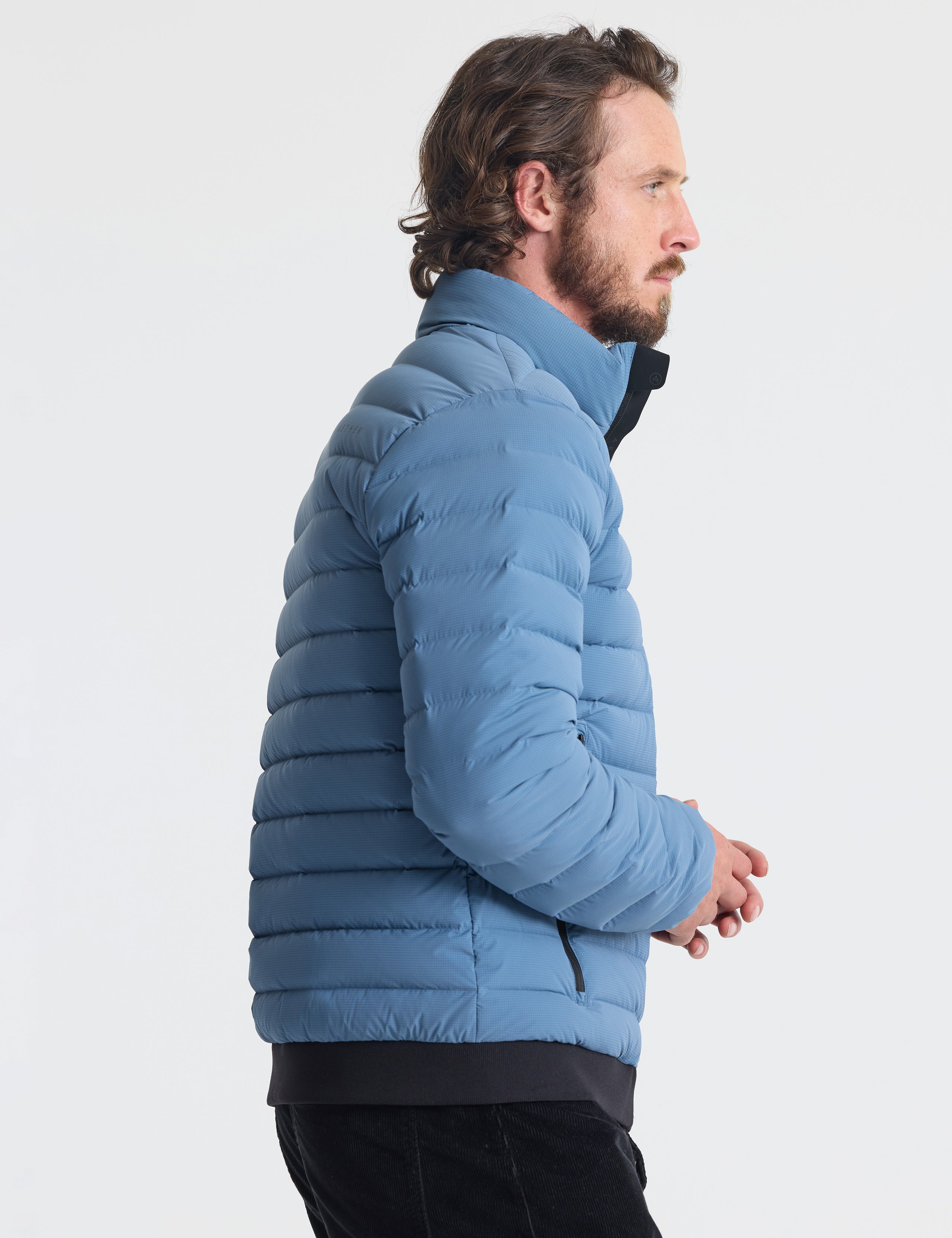 Right profile of man wearing Prospect Packable Down Jacket in Portal Blue from AETHER Apparel.