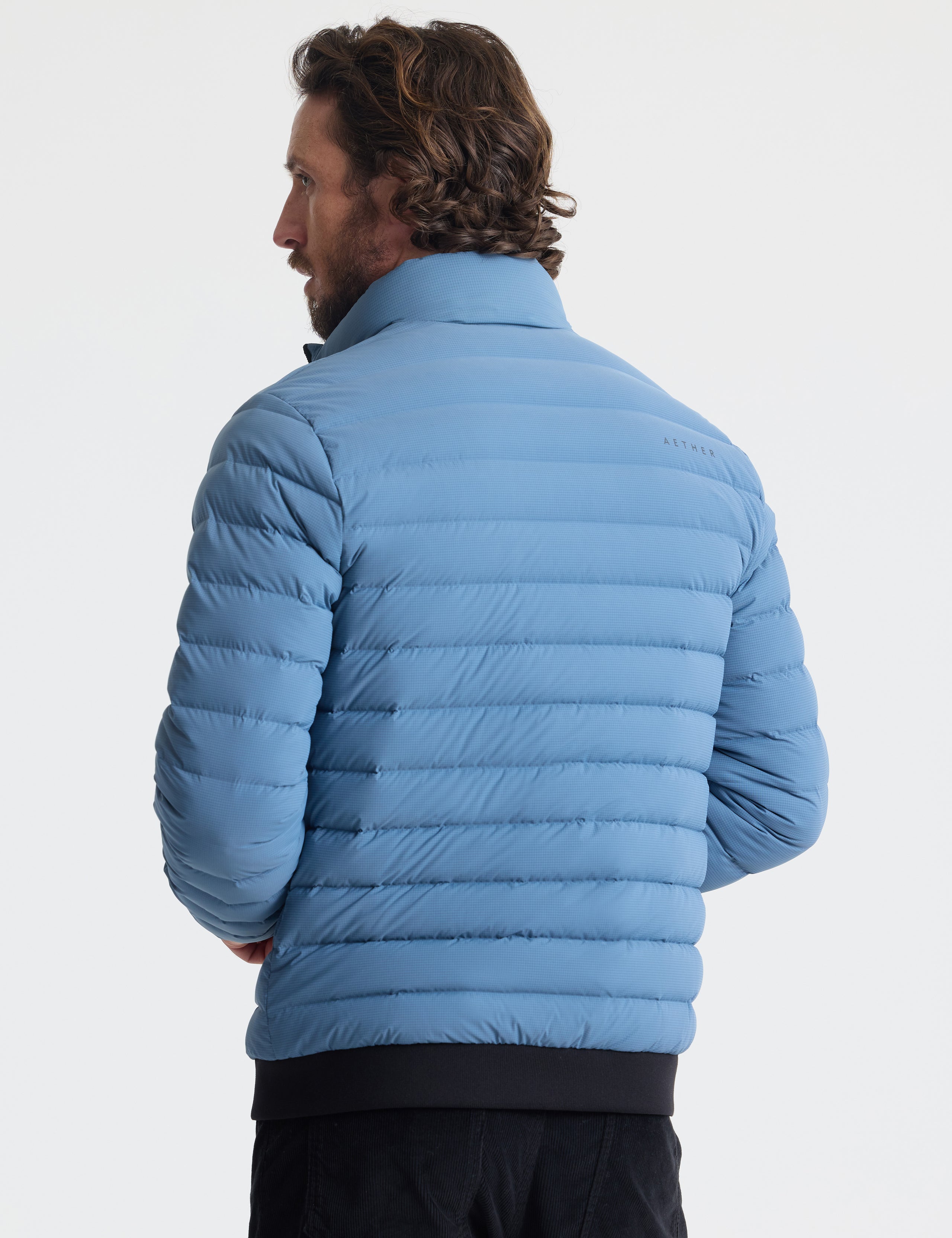 Rear view of man wearing Prospect Packable Down Jacket in Portal Blue from AETHER Apparel.