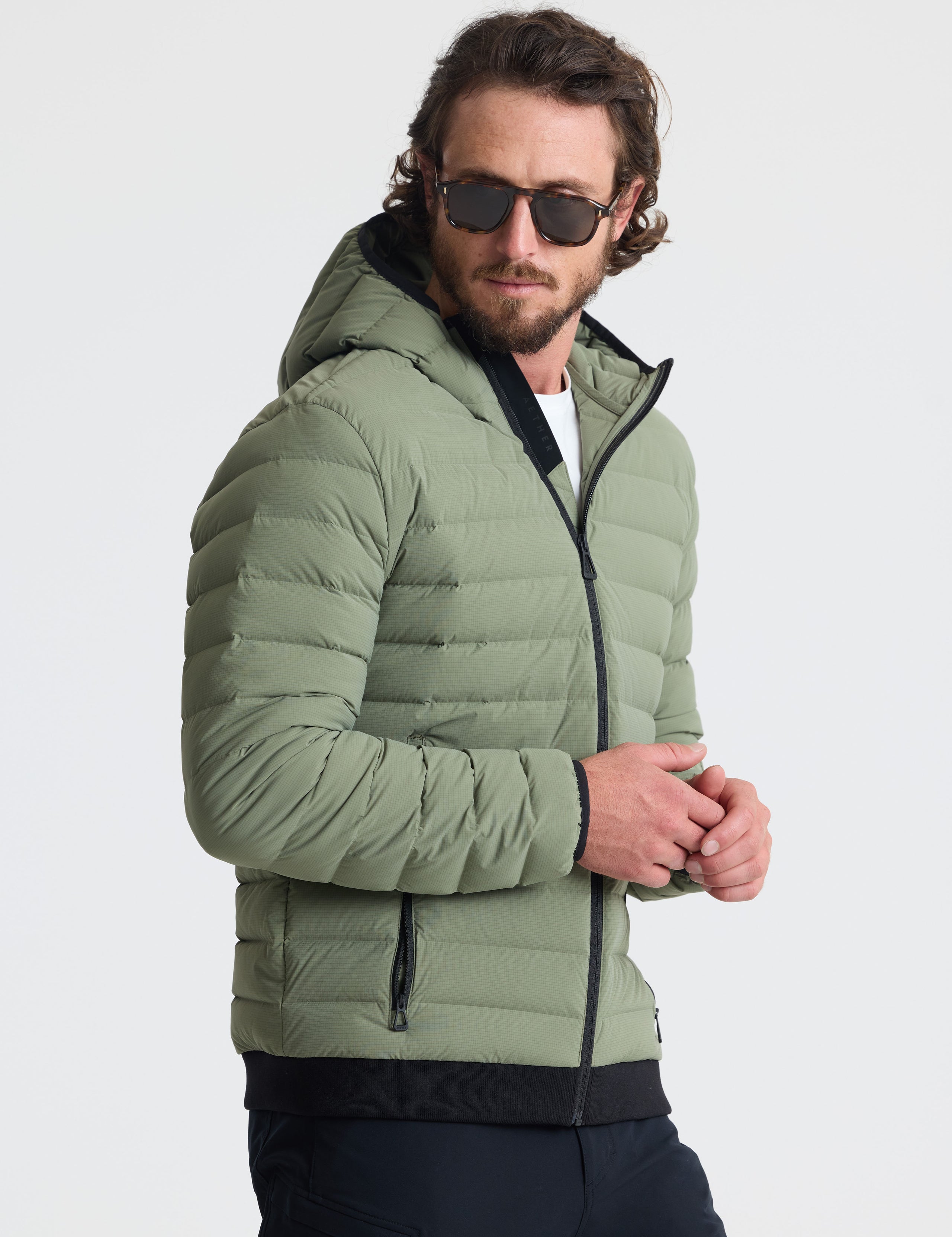 Angled view of man wearing Launch Full-Zip Hooded Jacket in Fern Green from AETHER Apparel.