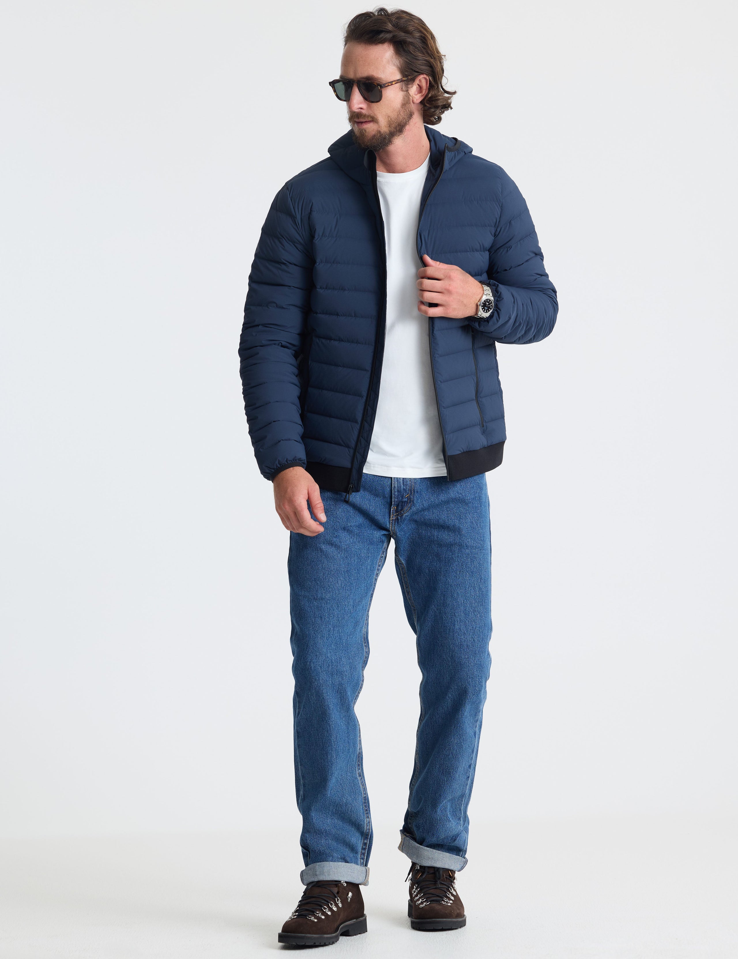 Full body view of man wearing Launch Full-Zip Hooded Jacket in Total Eclipse dark blue from AETHER Apparel.