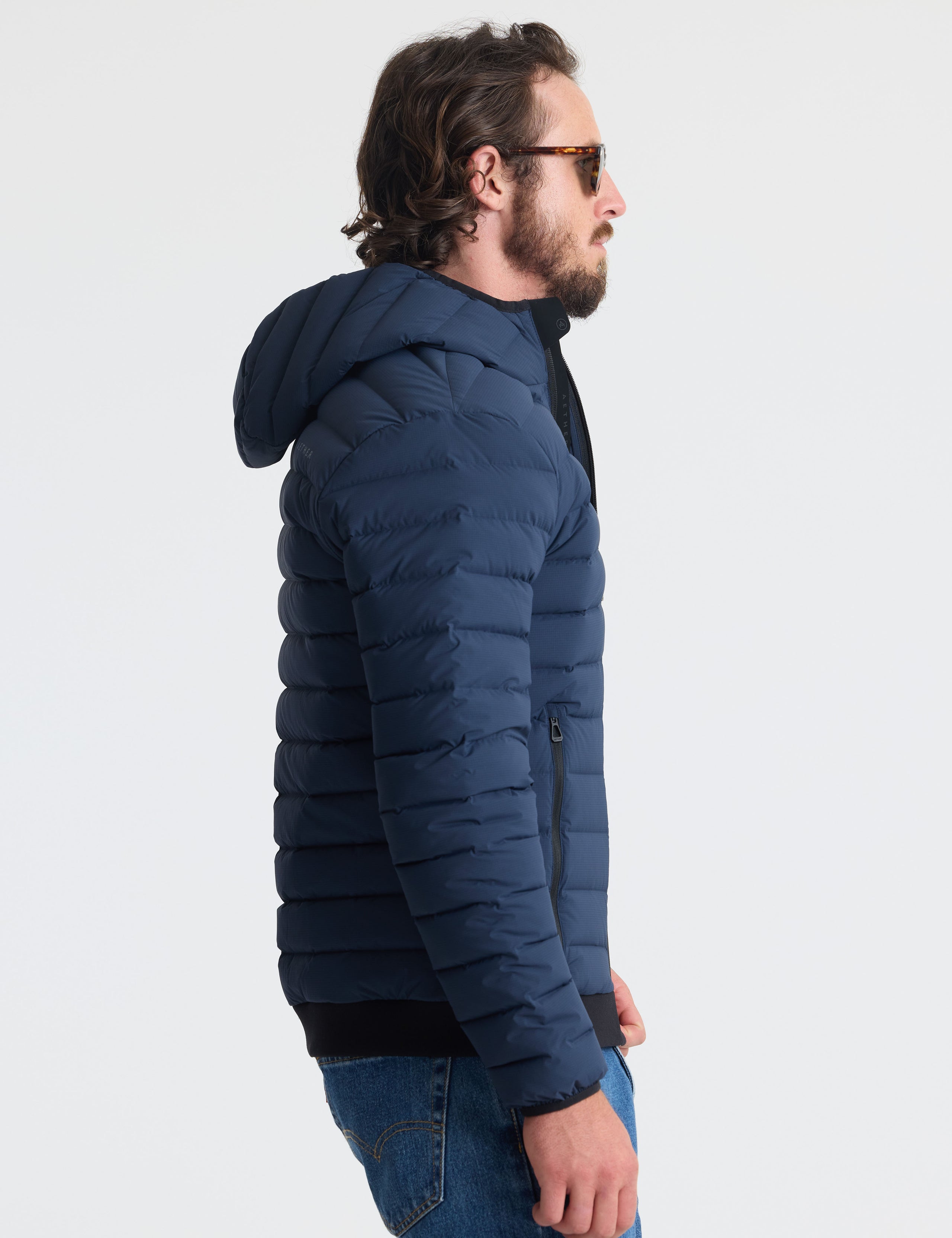Right profile of man wearing Launch Full-Zip Hooded Jacket in Total Eclipse dark blue from AETHER Apparel.