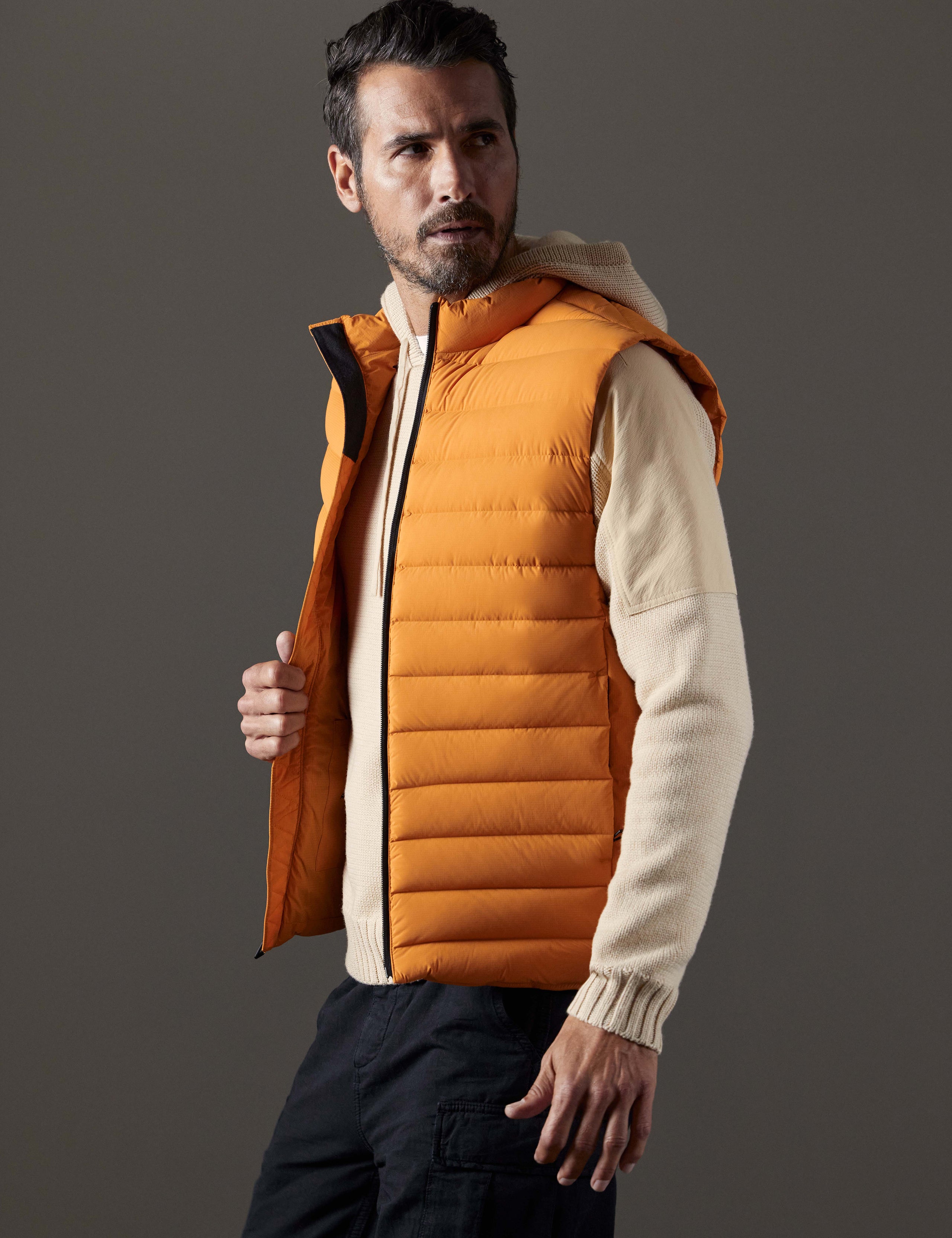 Side profile body view of man wearing Launch Vest in Midas Orange from AETHER Apparel.