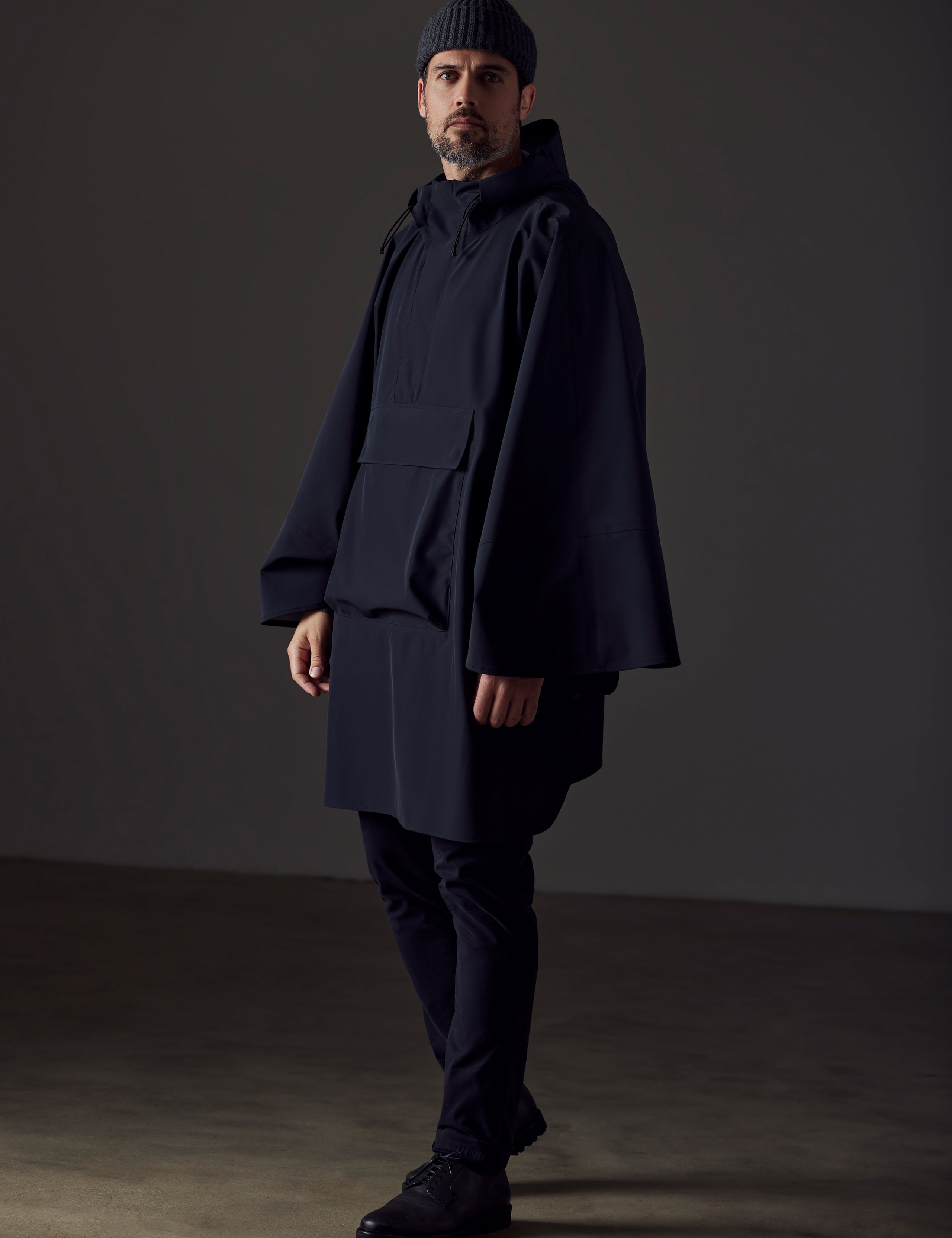 Full-body view of man wearing the Line Poncho in Onyx Black from AETHER Apparel.