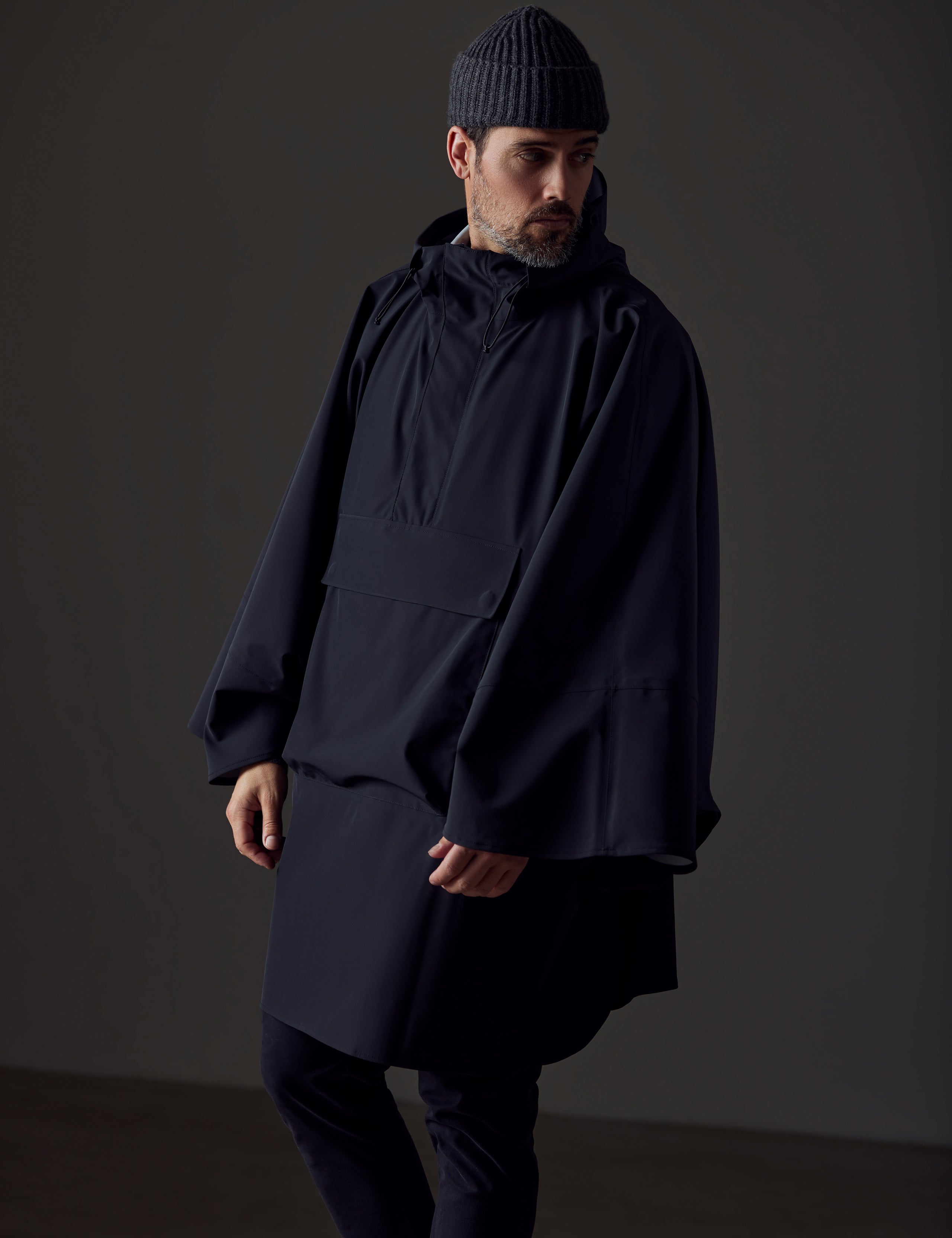 Front right-angled view of man wearing the Line Poncho in Onyx Black from AETHER Apparel.