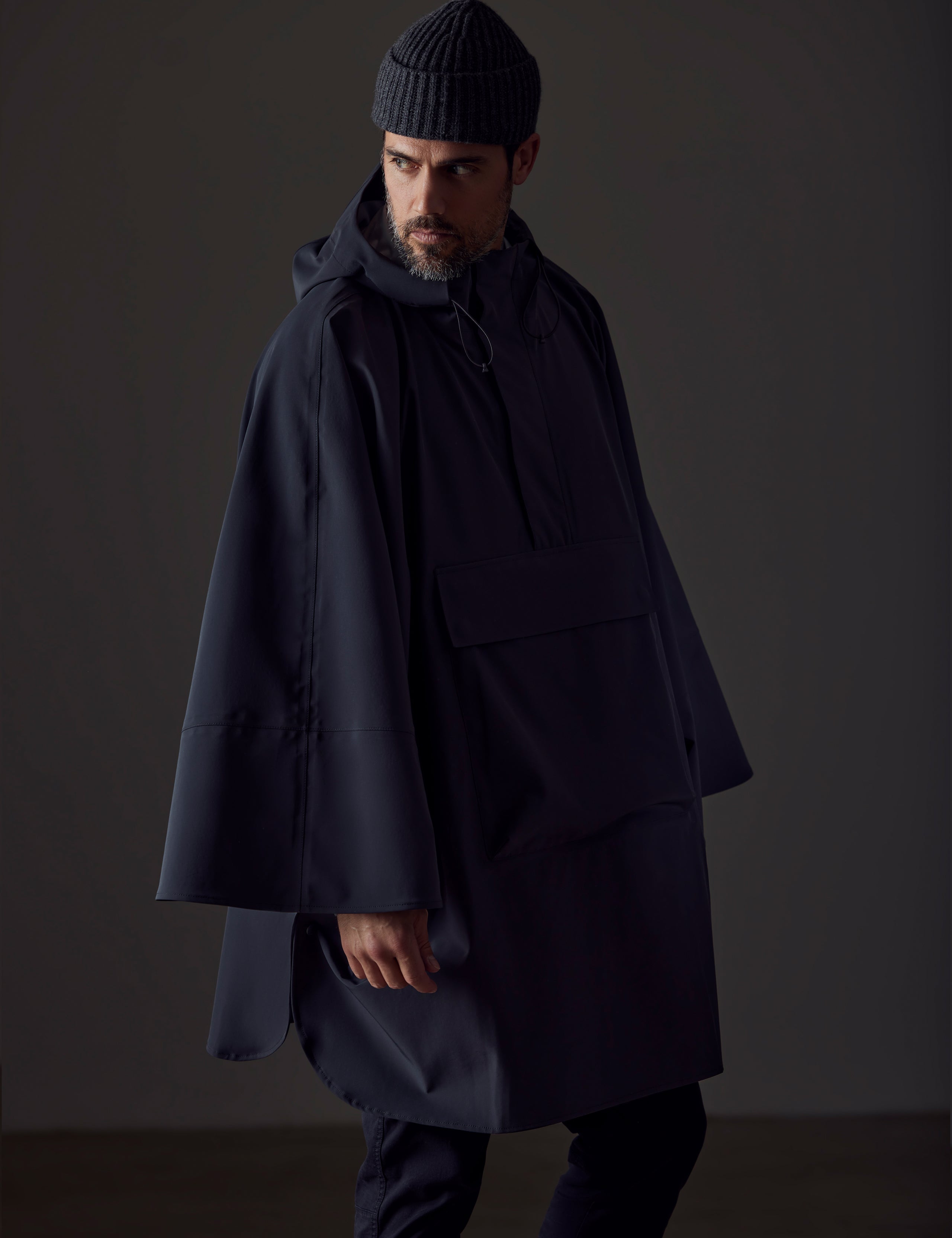 Front left-angled view of man wearing the Line Poncho in Onyx Black from AETHER Apparel.