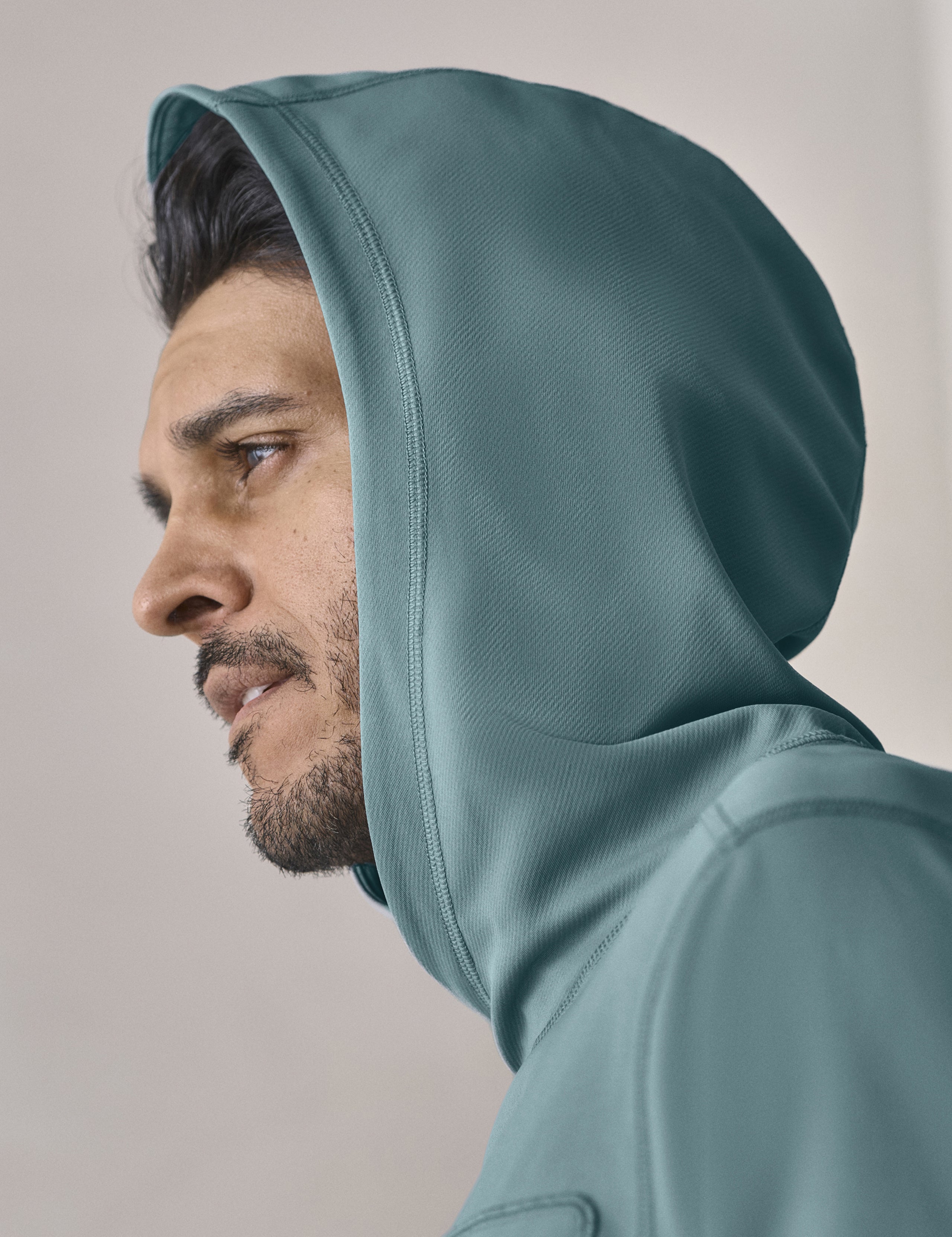 Closeup view of man with hood up wearing the Pacific Hooded Sun Shirt in Aqua Blue from AETHER Apparel.