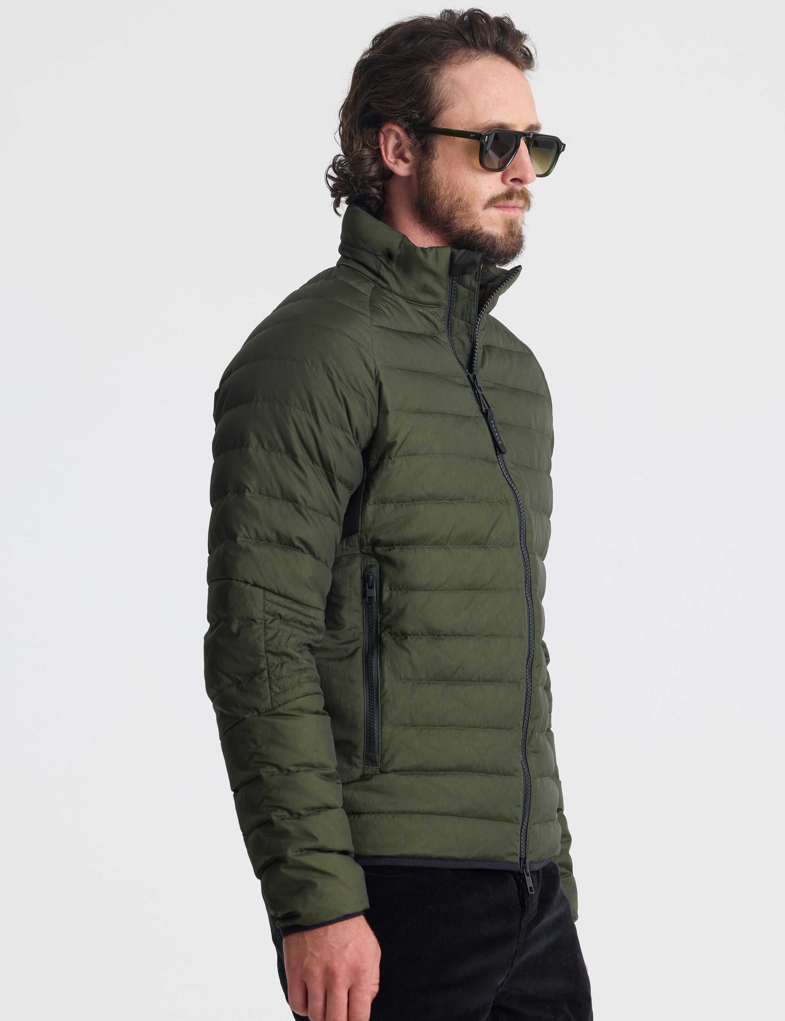 Angled view of man wearing Prospect Packable Down Jacket in Forest Green from AETHER Apparel.