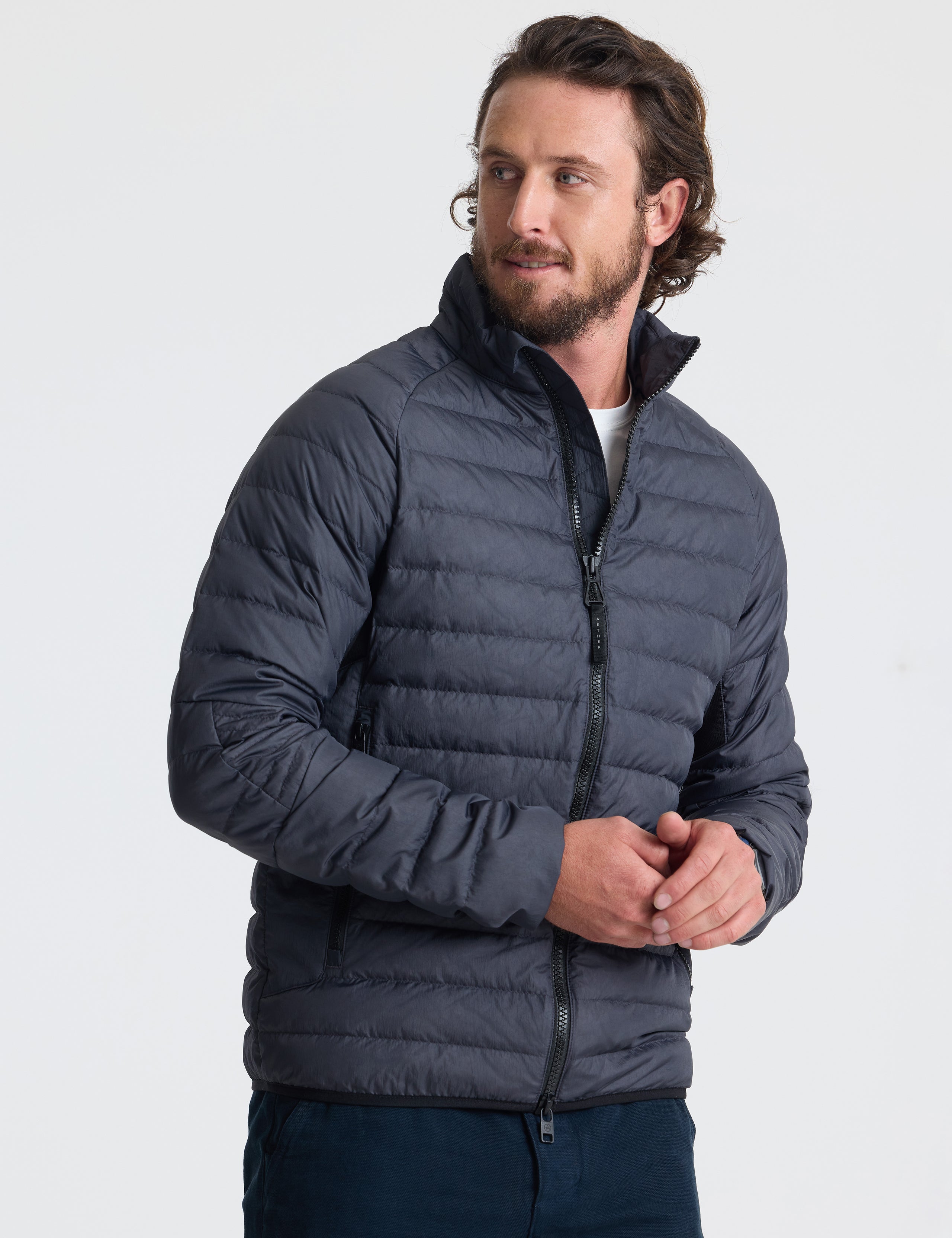 Angled view of man wearing Prospect Packable Down Jacket in Onyx Black from AETHER Apparel.