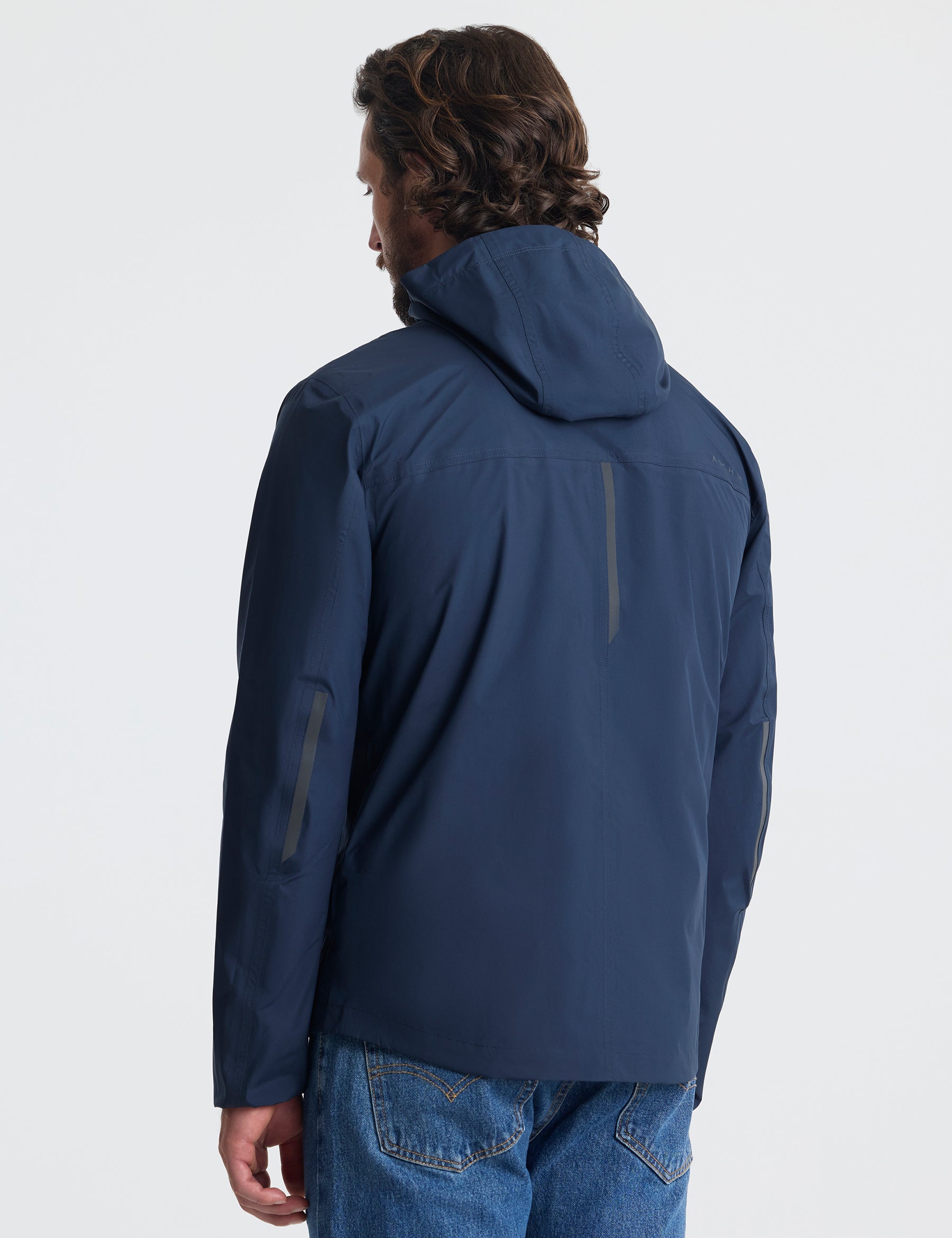 Rear view of man wearing Storm All-Weather Jacket in Total Eclipse dark blue from AETHER Apparel.